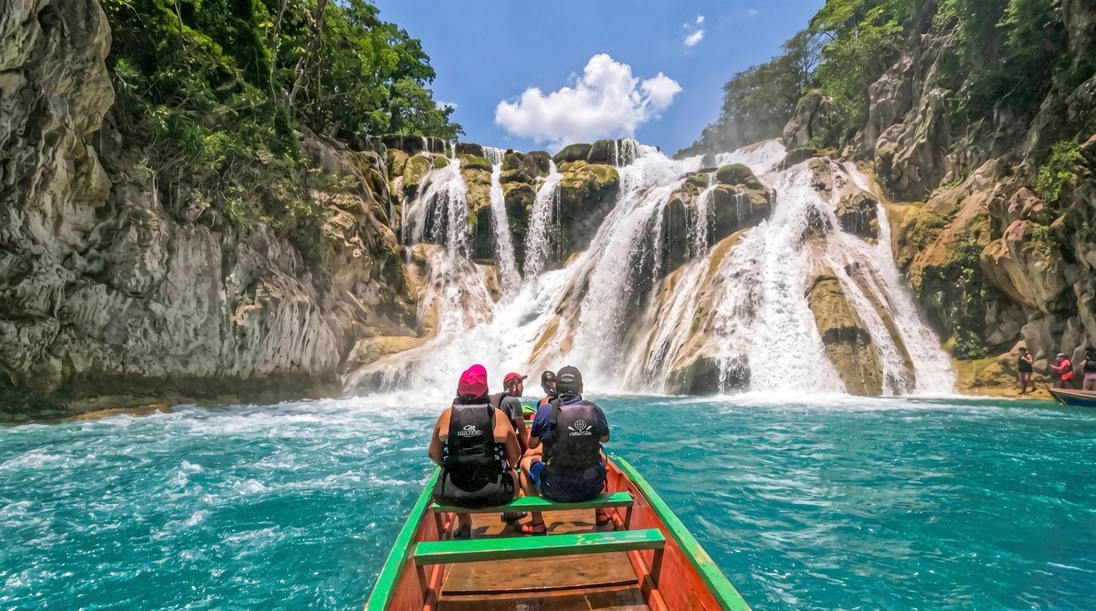 Panga en canoa acercándose a la Cascada del Meco por aguas turquesas