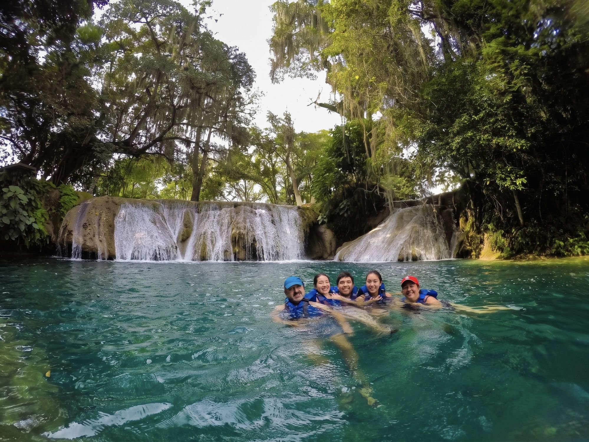 Dos mujeres sonriendo en el agua frente a las Siete Cascadas de Tamasopo