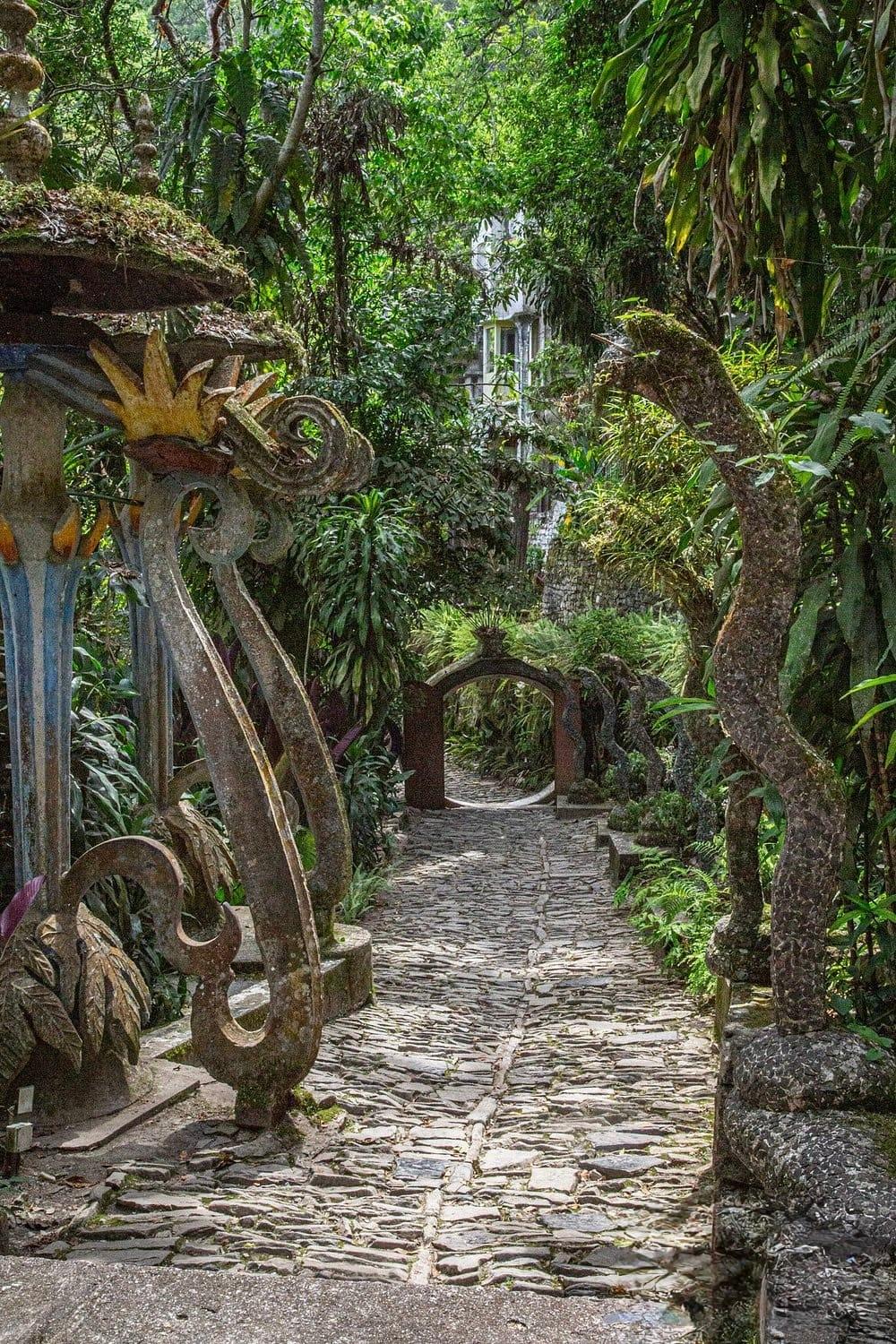 Las Pozas — sendero empedrado hacia el arco, entre esculturas