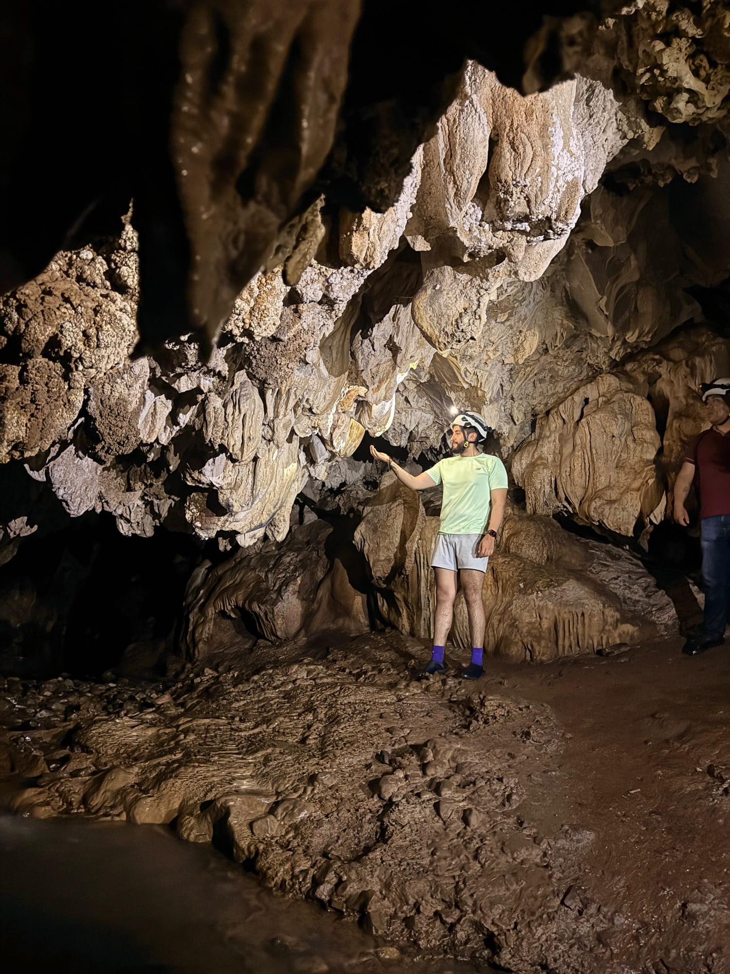 Xilo Cave — rock formations hanging overhead, lit by a headlamp