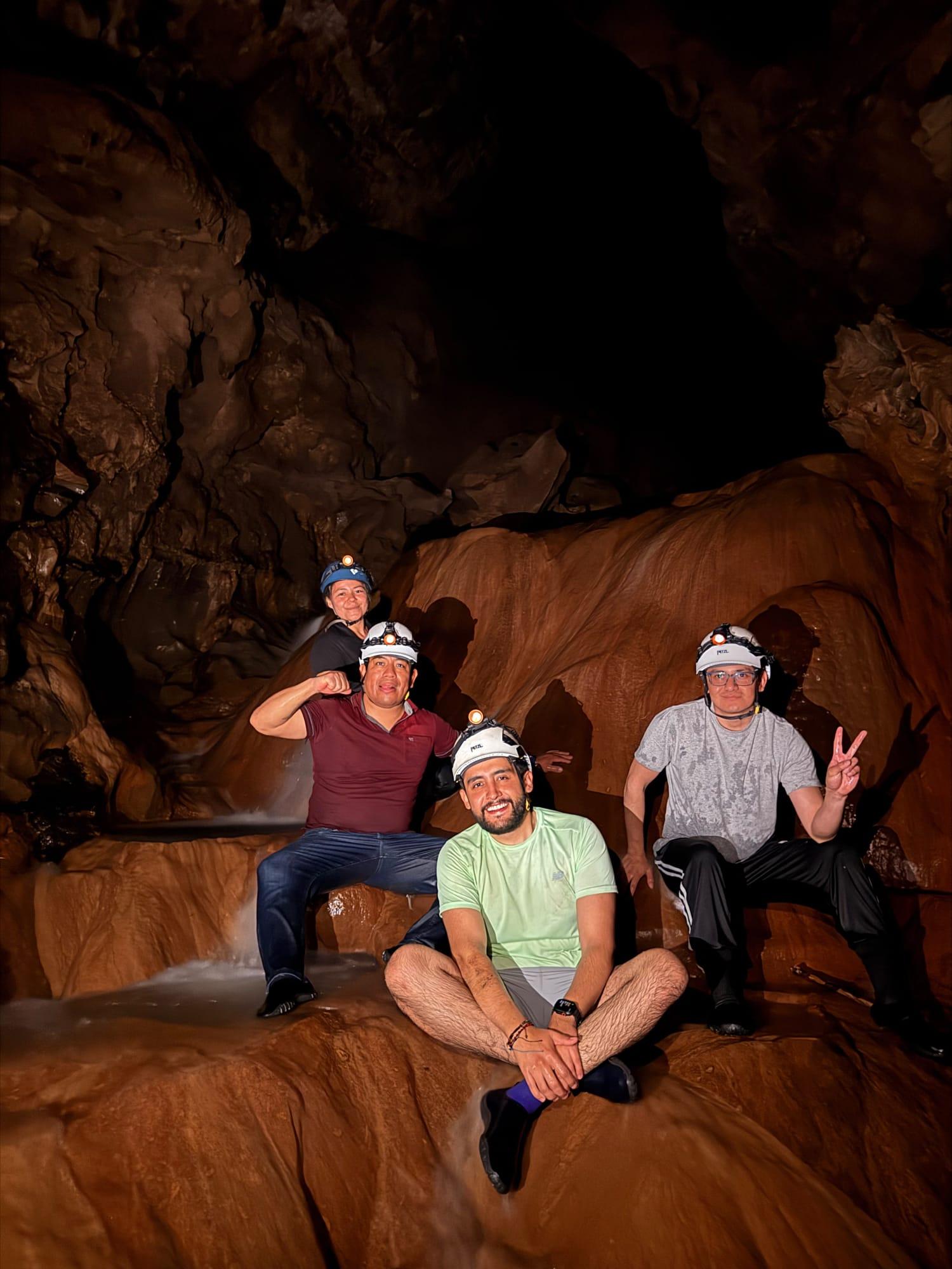 Xilo Cave — a group in helmets on a flowstone, next to a trickle of falling water