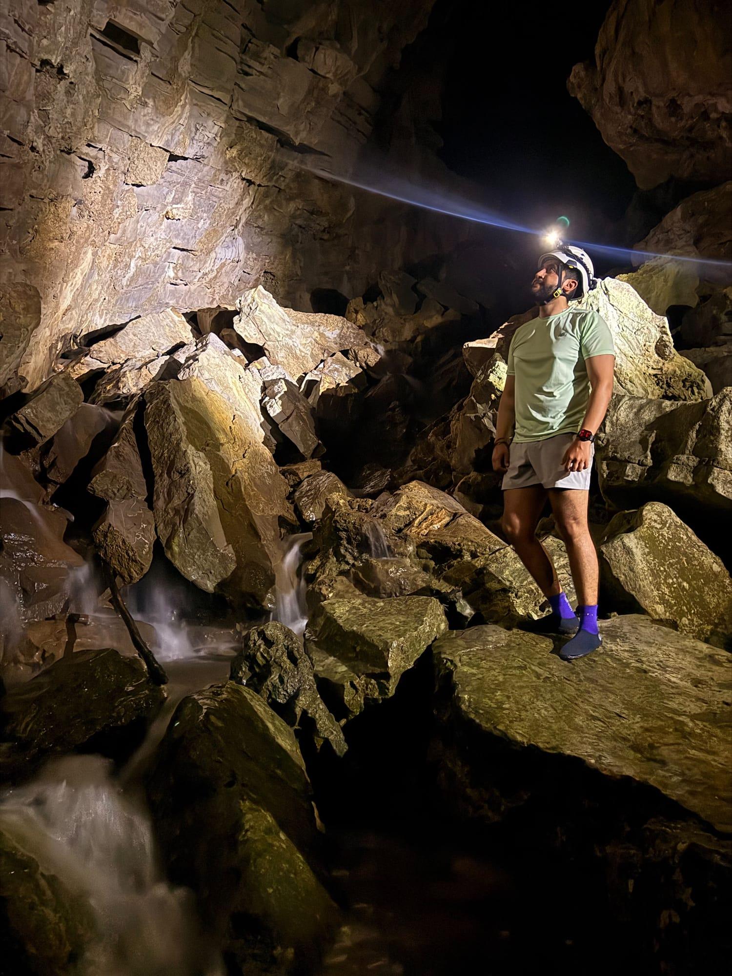 Xilo Cave — a helmet lamp lights up the rocks and the water running between them
