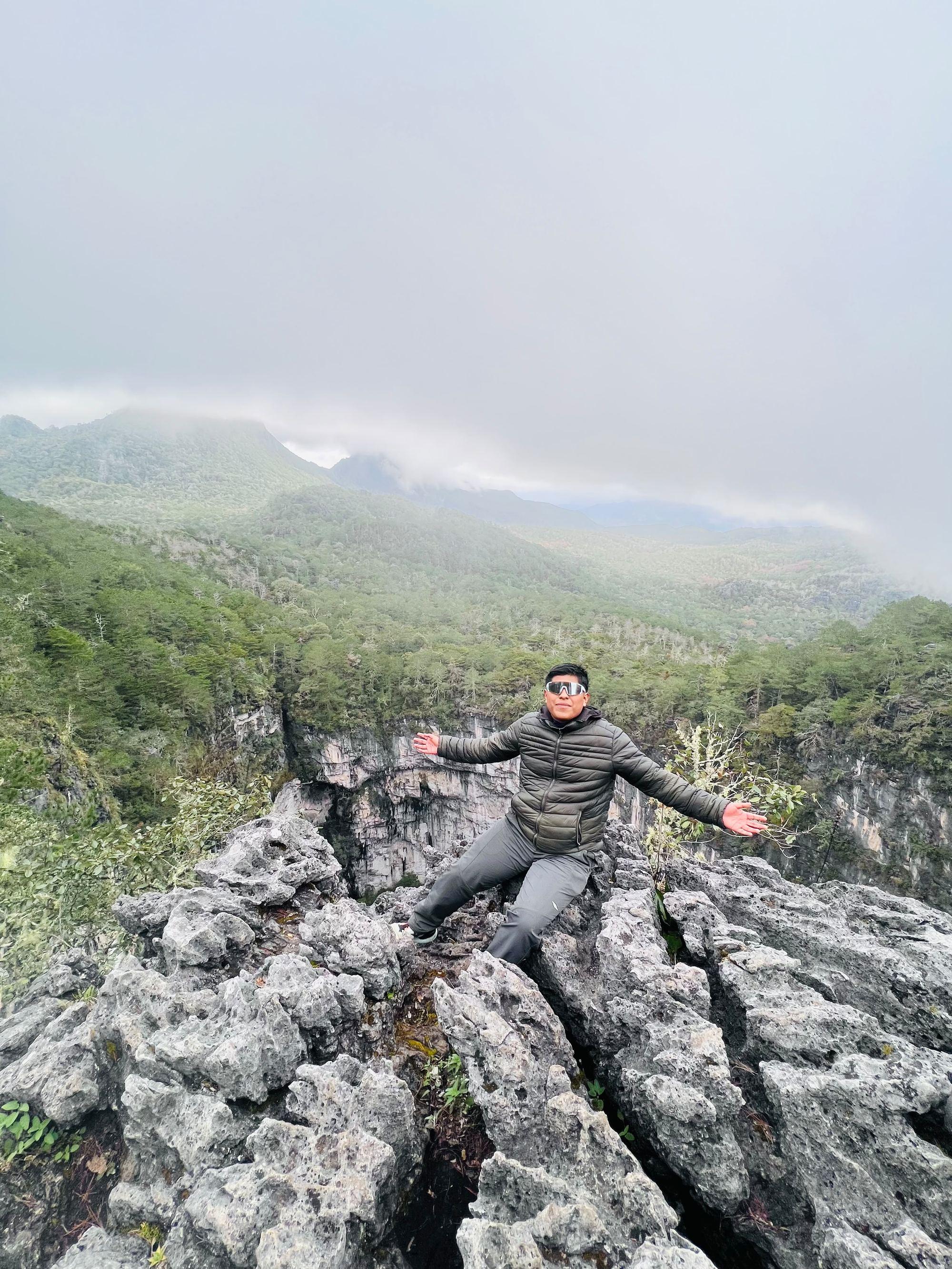 Guía de pie sobre las rocas kársticas del borde de la Olla de la Luz, entre la niebla del bosque