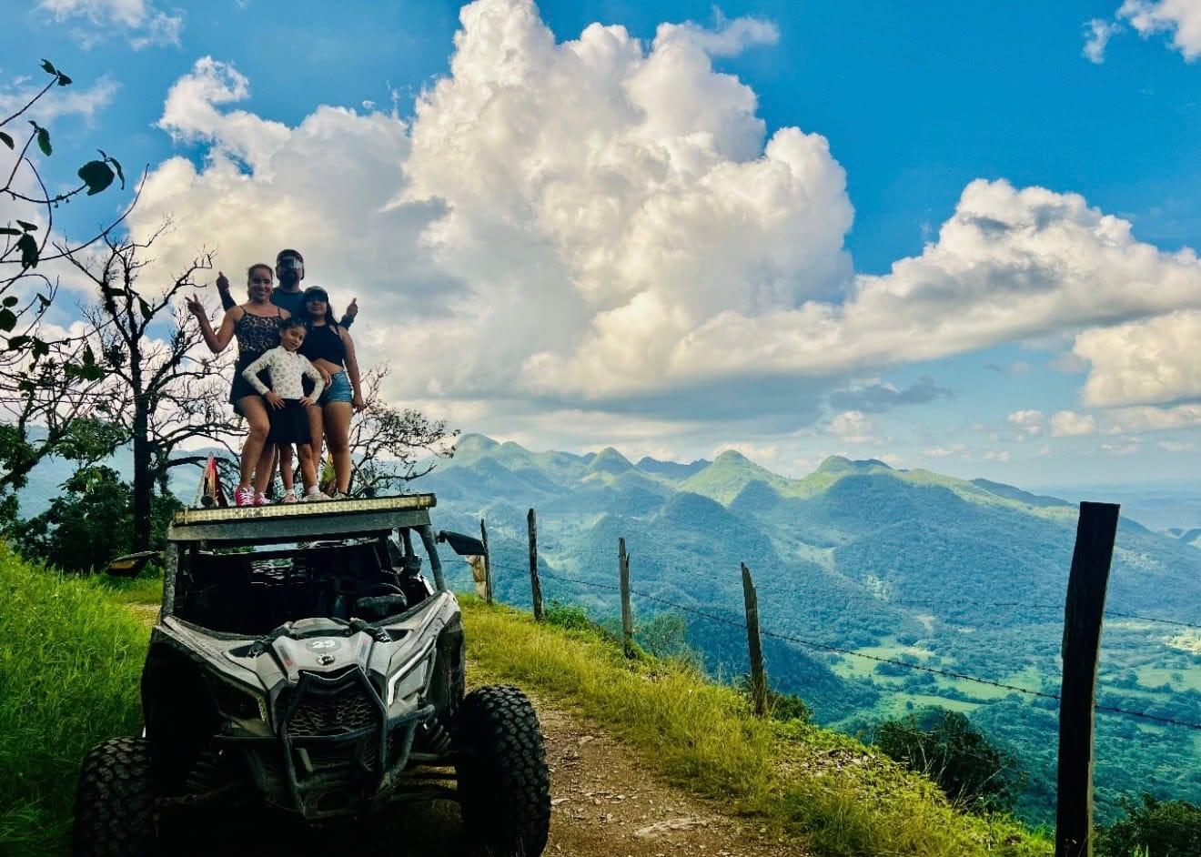 Mirador de la sierra — una familia de pie sobre el Maverick, con las montañas detrás