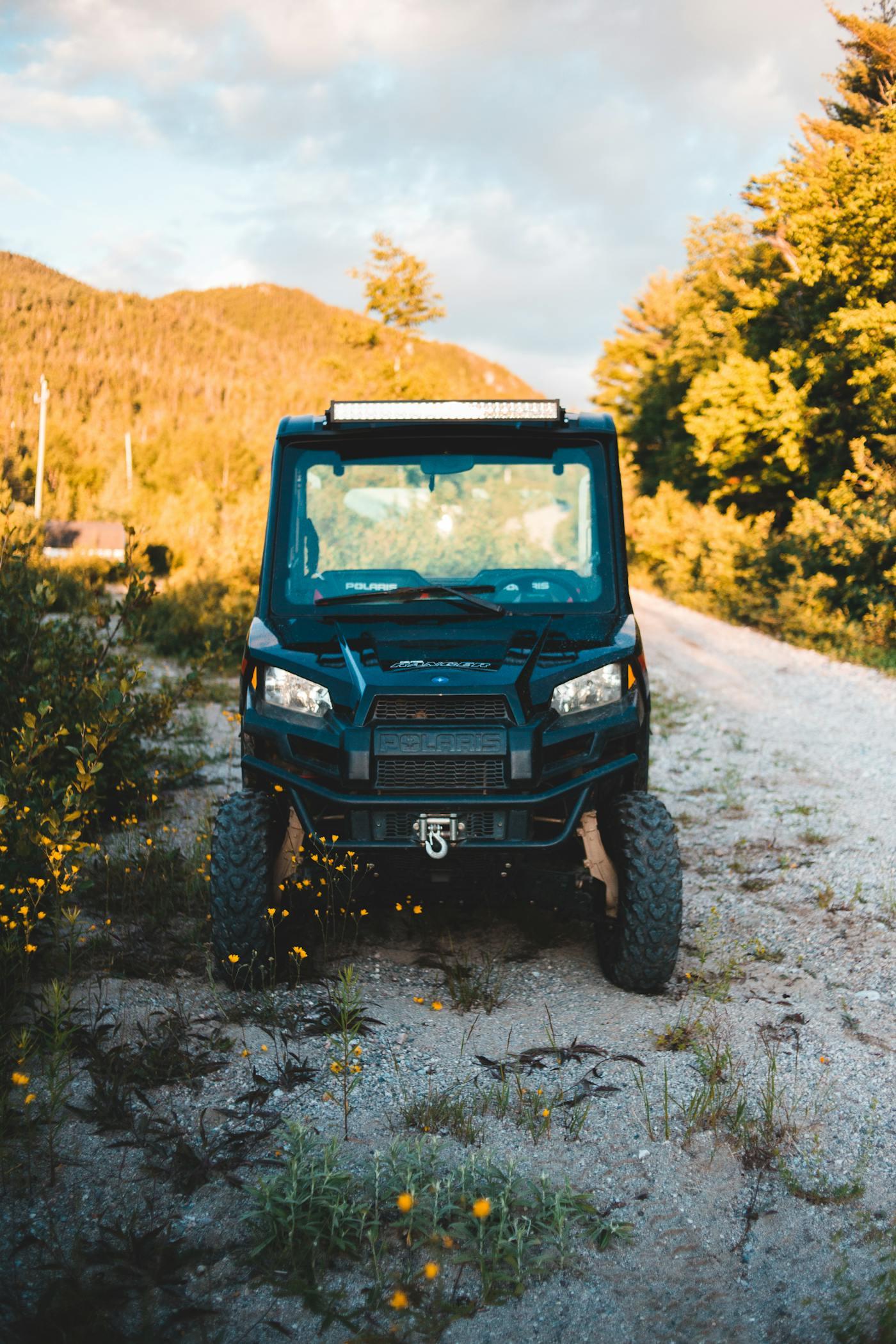 Vehículo todoterreno RZR de frente sobre un camino de terracería rodeado de naturaleza