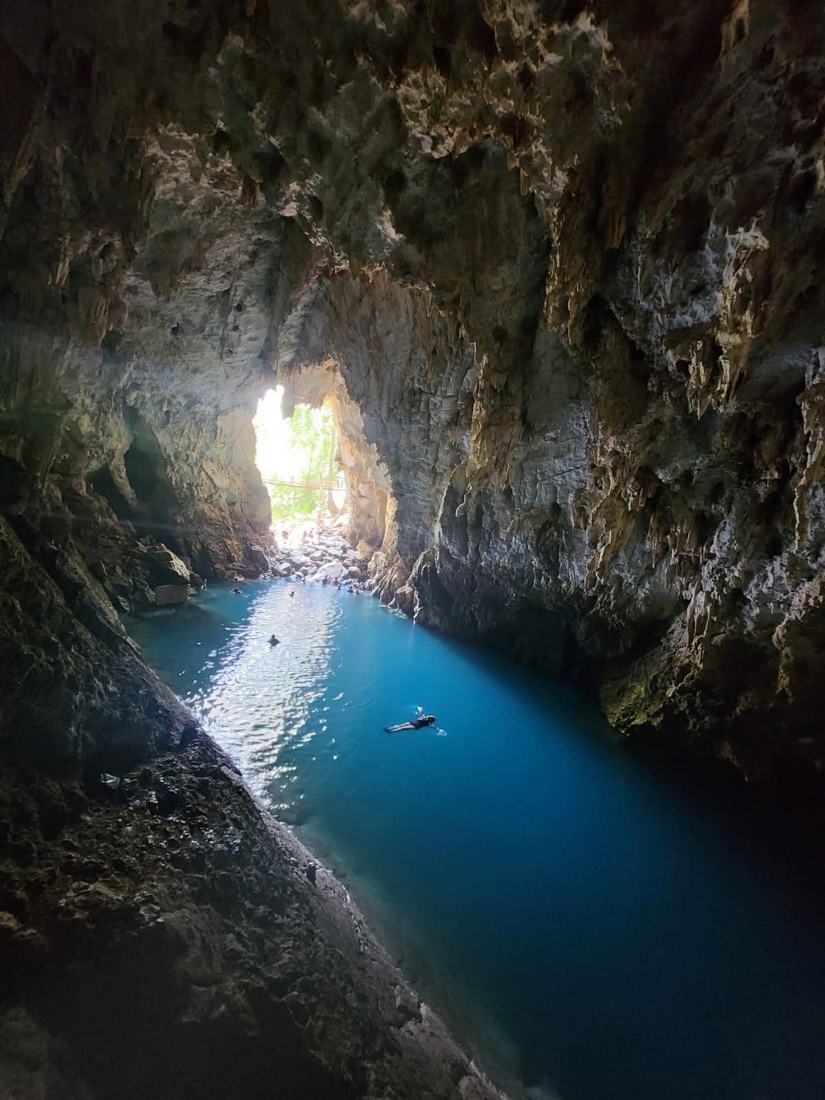 Cueva del Agua — la poza azul bajo la bóveda de roca, con gente nadando