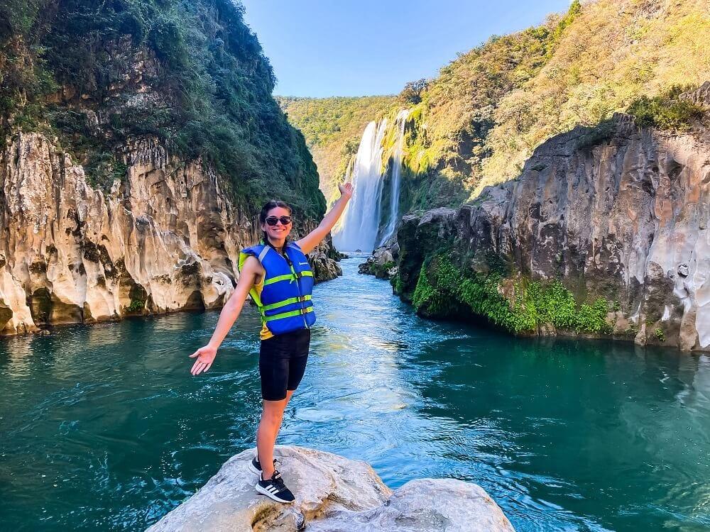 Cascada de Tamul — de pie sobre una roca del río, con la cascada detrás