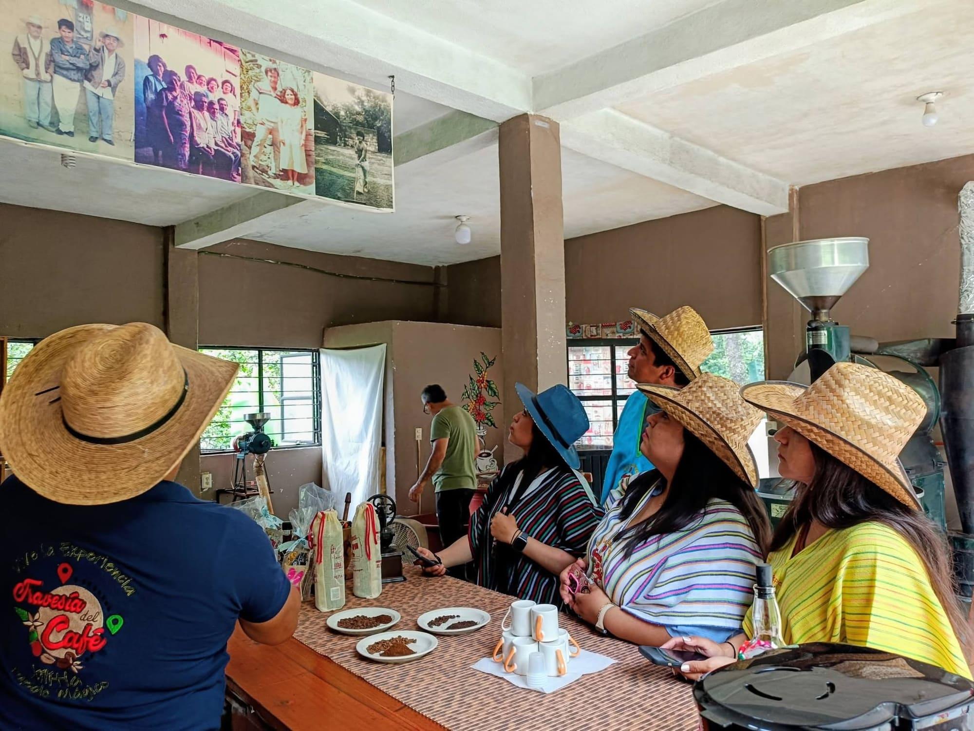 Visitantes escuchando la historia de la familia cafetalera dentro de la tostaduría, con las fotos antiguas colgadas del techo