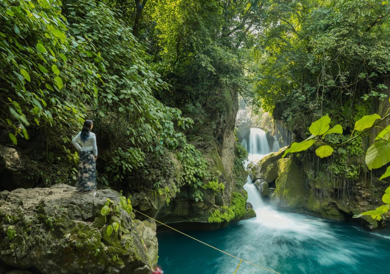 Mujer de espaldas frente a gran cascada blanca — Ruta Acuática Huasteca
