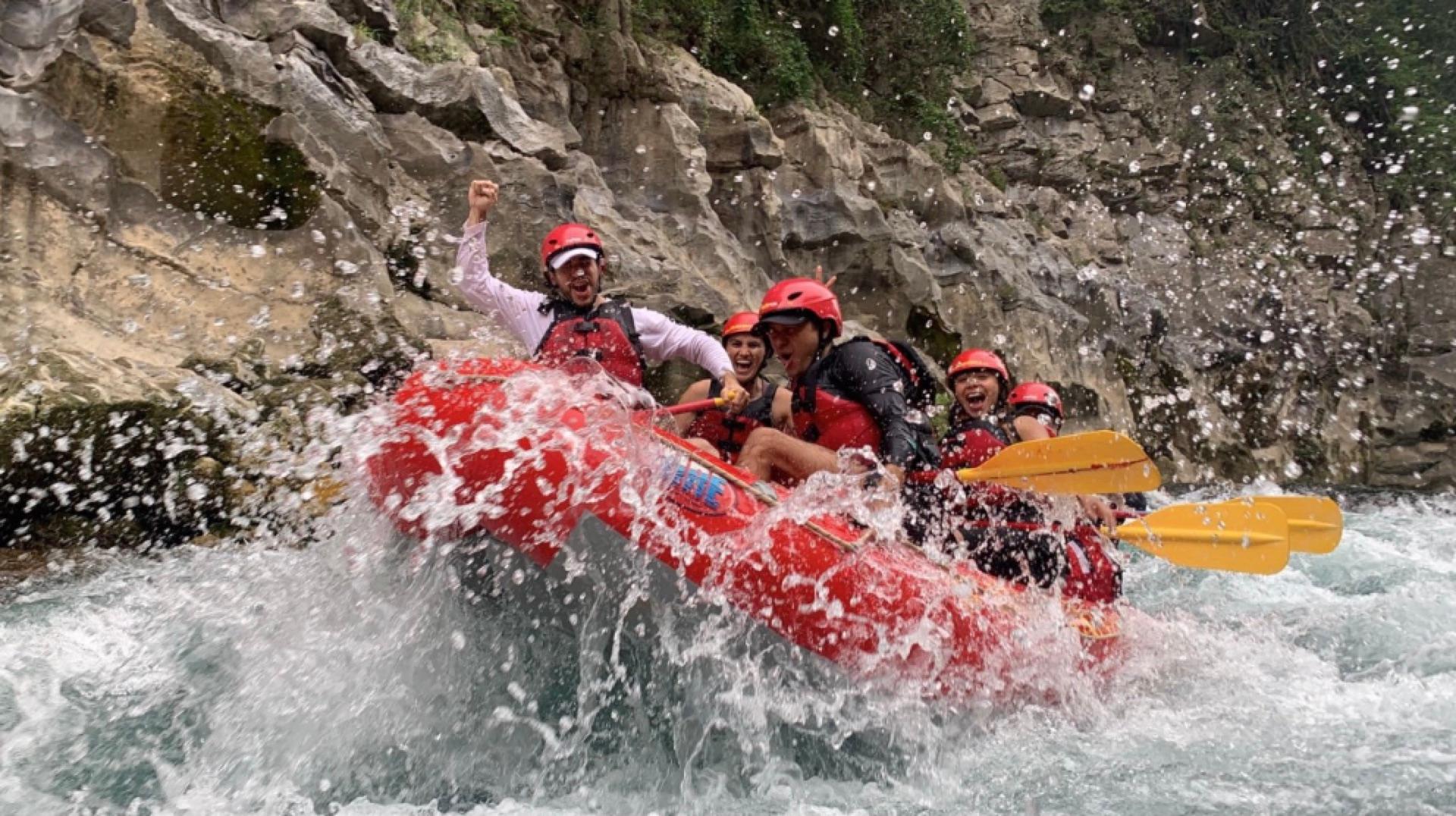 Tripulación celebrando con el puño en alto mientras su balsa roja cruza un rápido del Río Tampaón