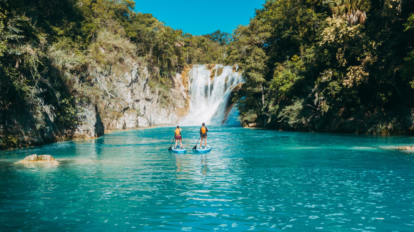 Pareja en paddle board frente a una cascada de aguas turquesas — itinerario de 3 días en la Huasteca Potosina
