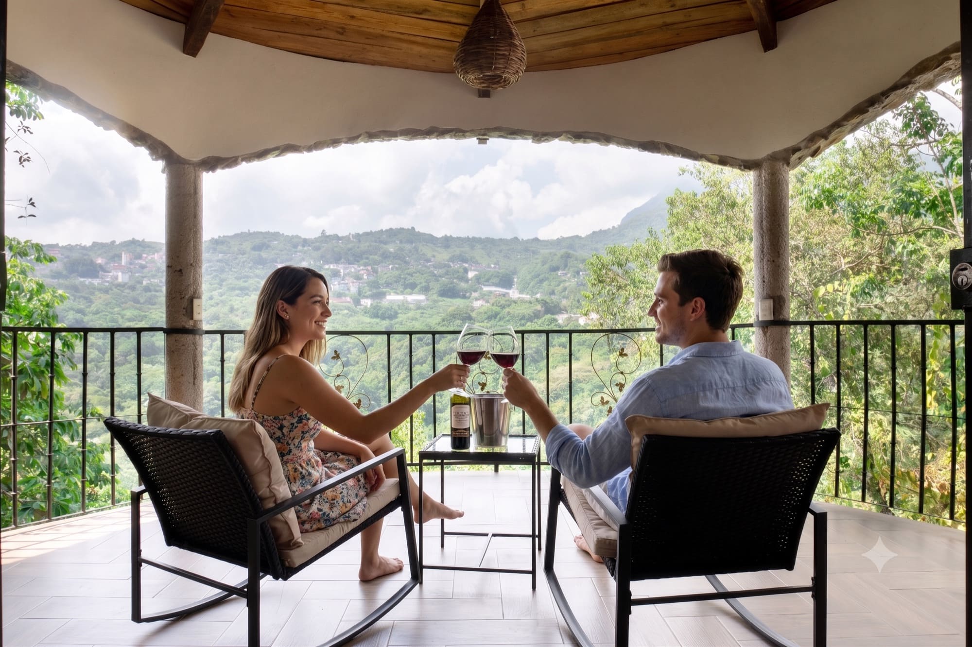 Pareja brindando con copas de vino tinto en la terraza de un hotel boutique con vista a la sierra de Xilitla, Huasteca Potosina
